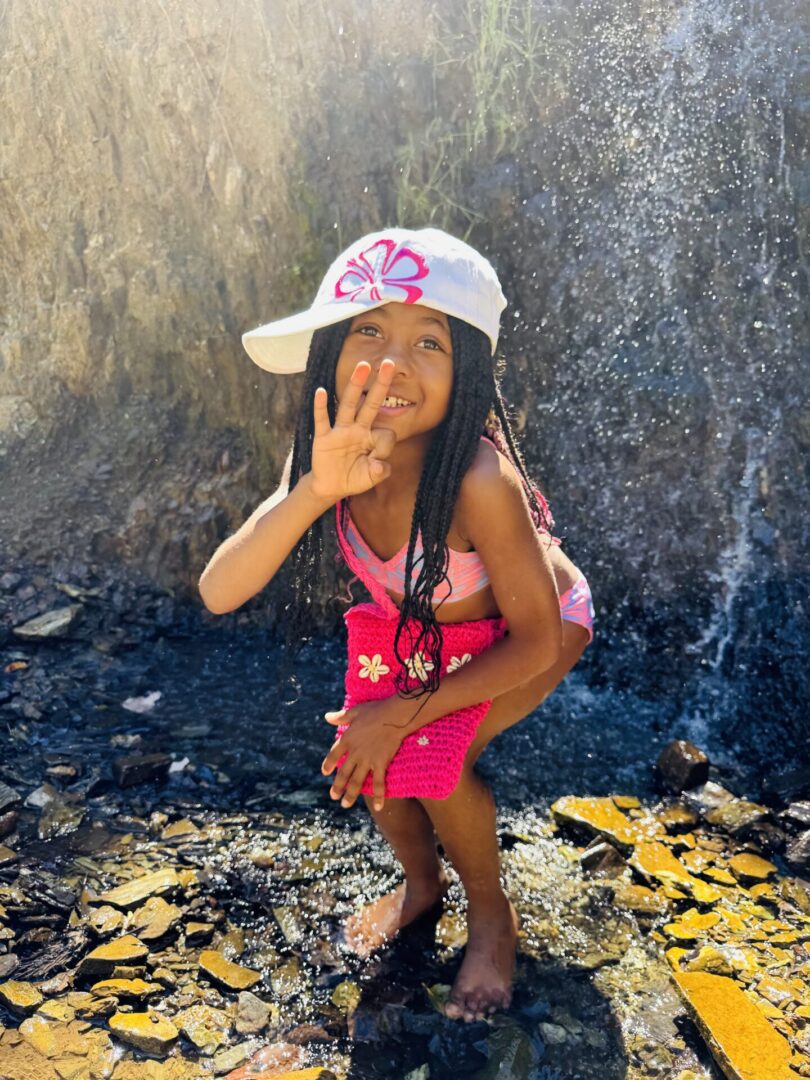 Smiling girl in hat by rocky waterfall